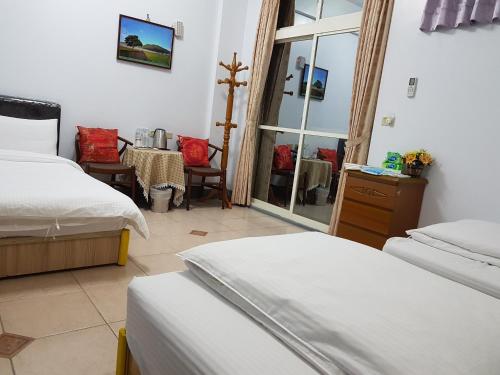 a bedroom with two beds and a table and a window at Fire B&B in Chishang