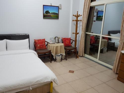 a bedroom with a bed and a table and chairs at Fire B&B in Chishang