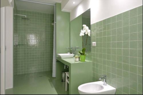 a green tiled bathroom with a sink and a mirror at Community Rooms & Wine in Favara