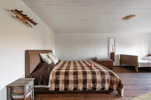 a bedroom with a bed with a blanket and a table at Pagulbis - Tavo namai in Klabiniai