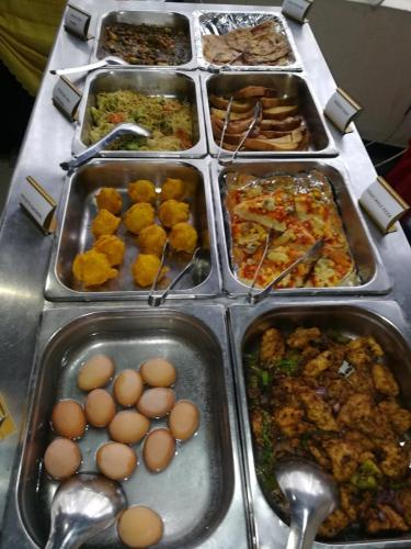 a buffet with many trays of food on a table at Urban Rose Hotel & Apartments in Dar es Salaam