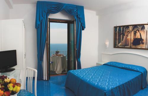 una camera con letto blu e specchio di Hotel Voce del Mare a Vietri