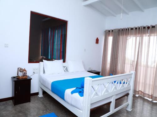 um quarto com uma cama branca e um cobertor azul em Fresh Wave Mirissa - Beach Front em Mirissa