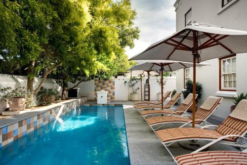 a swimming pool with chairs and an umbrella at Coopmanhuijs Boutique Hotel & Spa in Stellenbosch