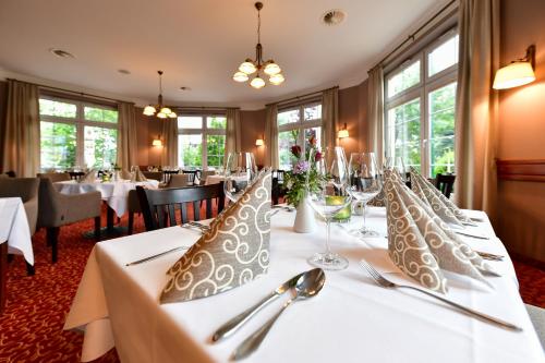 a dining room with white tables and silverware at Christinenhof & Spa - Wellnesshotel am Rande des Spreewalds in Tauer