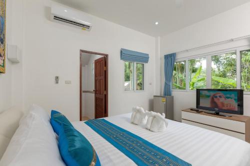 a white bedroom with a large bed and a tv at Patong Hill Estate 6 in Patong Beach