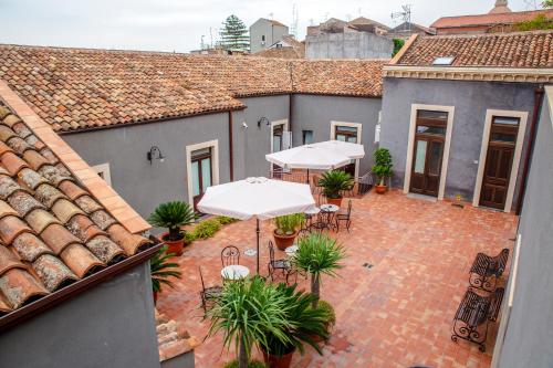 un patio al aire libre con mesas y sombrillas blancas en Dimora De Mauro en Catania