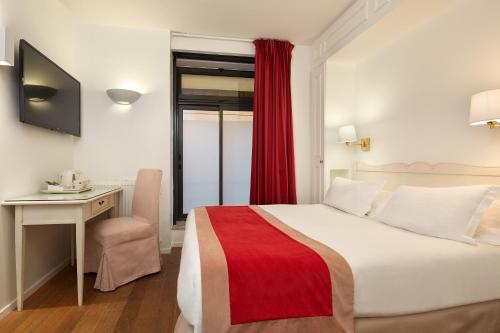a hotel room with a bed and a desk and a window at Austin's Arts Et Metiers Hotel in Paris