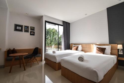 Habitación de hotel con 2 camas y mesa en B Boutique Residence en Surat Thani