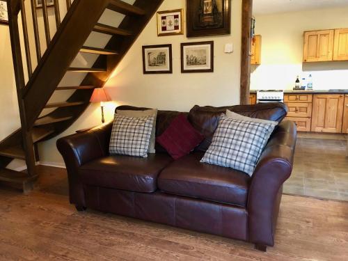 a brown leather couch in a living room with a staircase at Dupres House, Chavasse Farm, Somme Battlefields in Hardecourt-aux-Bois