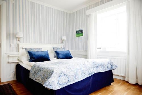 a bedroom with a large bed with blue pillows at Knistad Herrgård in Skövde