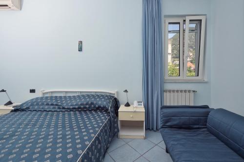 um quarto com uma cama e um sofá ao lado de uma janela em Maison Raphael em Minori