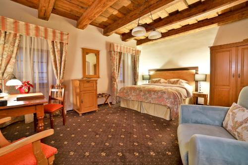 a bedroom with a bed and a desk and a couch at Questenberg Hotel in Prague