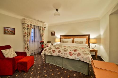 a bedroom with a bed and a red chair at Questenberg Hotel in Prague