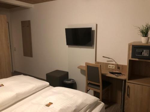 a hotel room with a bed and a desk and a tv at Heeren's Hotel Garni in Bensersiel