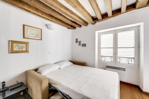 a white bedroom with a bed and a window at Saint Germain des Près UNIT 002 in Paris