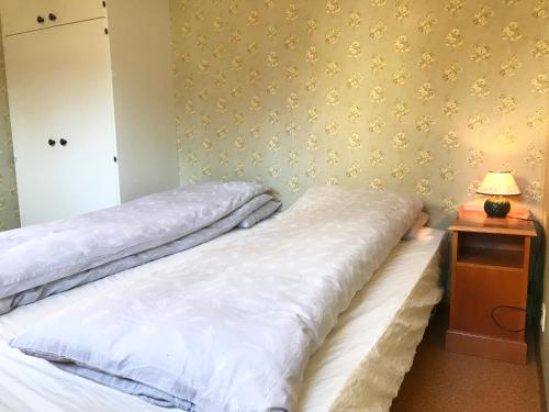 a bedroom with two beds and a night stand with a lamp at Villa Holmen 2 - Ground floor apartment in Balestrand