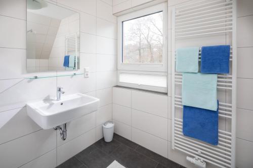 ein weißes Bad mit einem Waschbecken und einem Fenster in der Unterkunft Deniz - Blick in Norderney