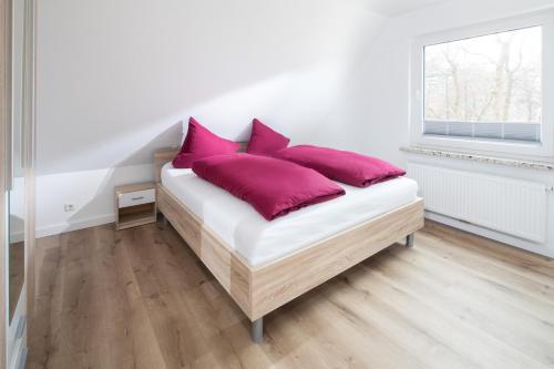 1 cama con almohadas moradas en una habitación blanca en Deniz - Blick en Norderney