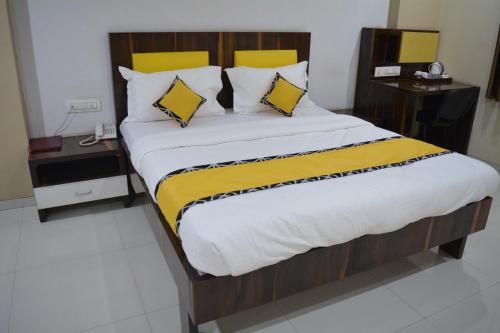 a large bed with yellow and white sheets and pillows at Dhuri Resort in Vasai