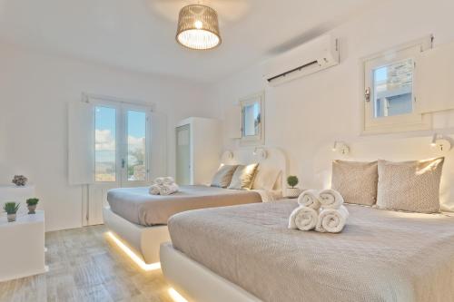 Duas camas num quarto branco com janelas em Lux View Villas em Kyra Panagia