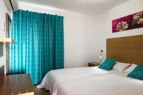 a bedroom with a bed and a blue curtain at Apartamentos Villa Canaima in Puerto del Carmen