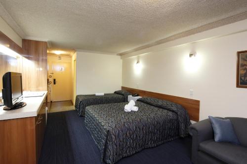 a hotel room with a bed and a flat screen tv at Windsor Lodge in Perth