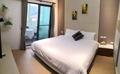 a bedroom with a large white bed and a balcony at Love Happiness Inn in Suao