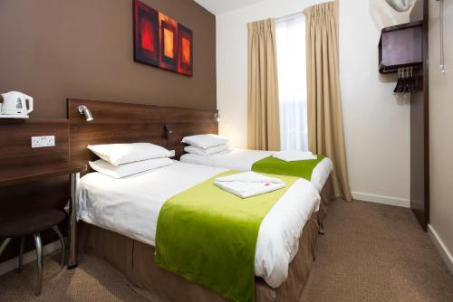 Una habitación de hotel con dos camas y un escritorio. en Marble Arch Inn, en Londres