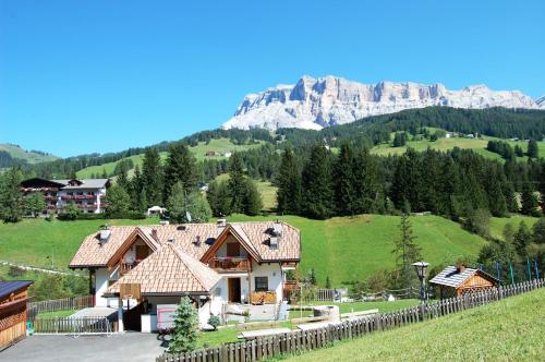 a house with a fence and a mountain in the background at Chalet alla Cascata in Badia