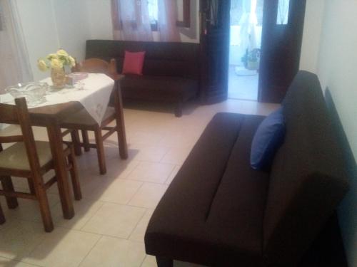 a living room with a table and a black couch at Nikos and Eva Studios in Symi