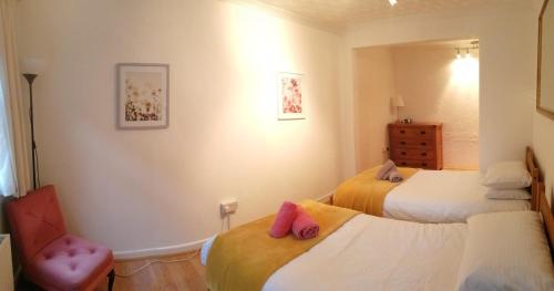 1 dormitorio con 2 camas y 1 silla en TheAnnexeatLongview, en Lytchett Matravers