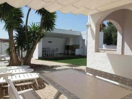 Un patio con sillas blancas y una casa. en Casa Albahaca, en El Palmar