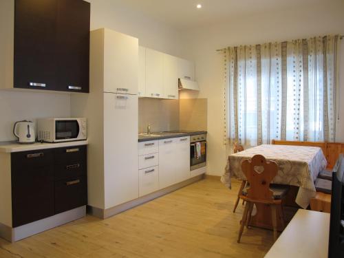 a kitchen with white cabinets and a table with a microwave at Appartamenti Col Rodella by AMA Val di Fassa in Campitello di Fassa