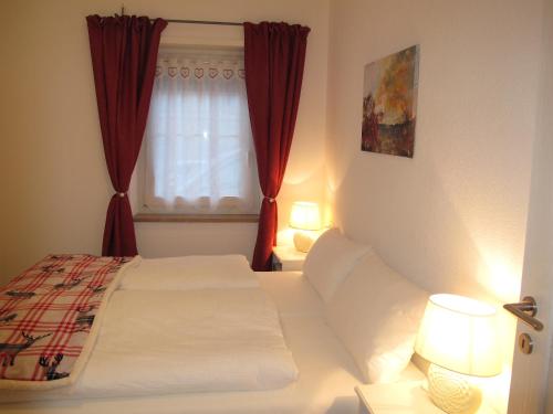a bedroom with a bed and a window with red curtains at Appartamenti Col Rodella by AMA Val di Fassa in Campitello di Fassa