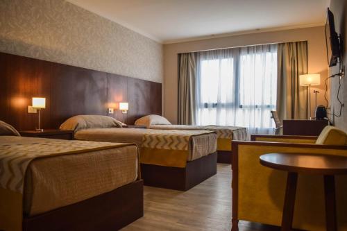 a hotel room with three beds and a window at Platinum Hotel Casino in Villa Ángela