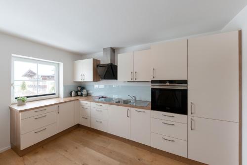 a white kitchen with white cabinets and a window at Wawies Apartments in Flachau