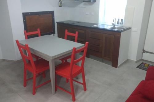 a kitchen with a table and four red chairs at Casa "L'Alloria" in Fezzano