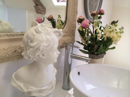 a statue of a bust next to a sink in a bathroom at Little Campden House in Chipping Campden