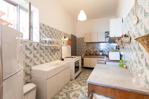 kuchnia z białymi szafkami oraz niebieską i zieloną tapetą w obiekcie Casa Annalu w mieście Positano