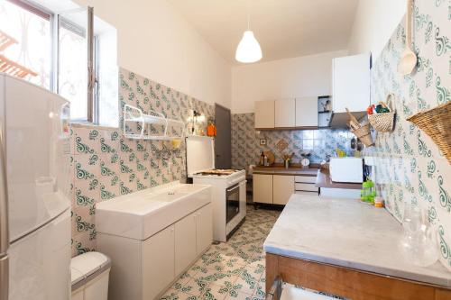 una cucina con armadi bianchi e carta da parati blu e verde di Casa Annalu a Positano