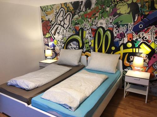 a room with two beds in front of a colorful wall at Wondervolles zuhause auf Zeit in Moers
