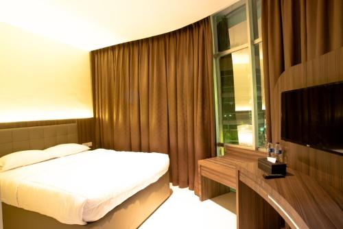 a bedroom with a bed and a desk and a television at AK Hotel Nagoya Hill in Batam Center