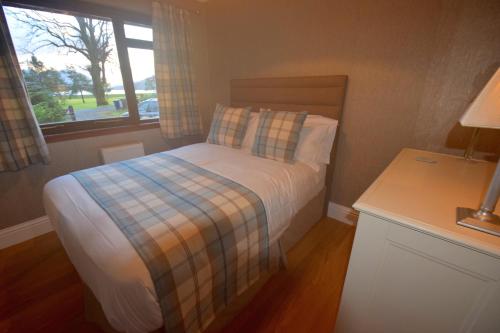 a small bedroom with a bed and a window at Crann Mhor Holiday Home in Lochgoilhead