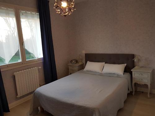 a bedroom with a bed and a window and a chandelier at Hotel du Commerce Chez Stéphane in Roumazières