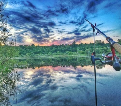 a person is holding a fishing rod on a lake at Kambarių nuoma Kačerginės kurorte in Kačerginė