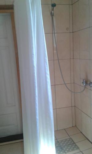 a shower with a white shower curtain in a bathroom at Гостьовий дім у Почаєві in Pochayiv