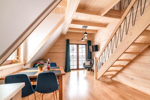 an attic room with a staircase and a table and chairs at Apartamenty Augustynówka in Brzegi