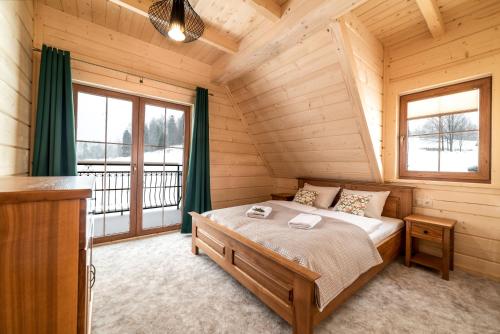 a bedroom with a bed in a log cabin at Apartamenty Augustynówka in Brzegi