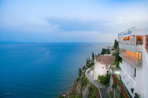 a building on a cliff next to the water at Hotel Voce del Mare in Vietri sul Mare